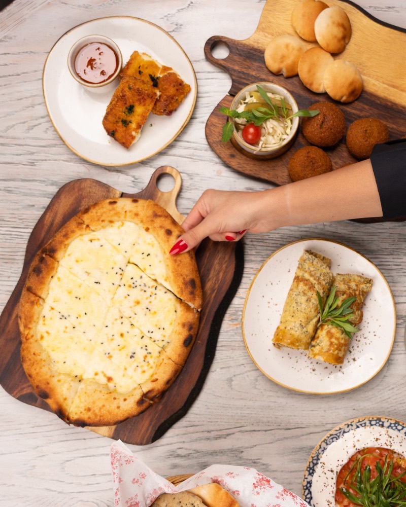 Cheese manakish on a wooden board among other dishes