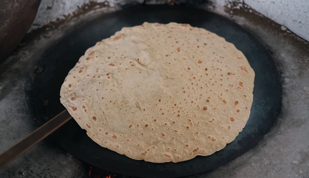 Thin dough baking on a hot dark griddle
